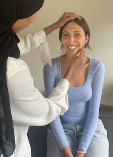 Photo of woman being treated sitting on treatment table. The osteopath has her hands on the patients head and jaw.